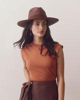 Person wearing a hat and sleeveless top looking to the side