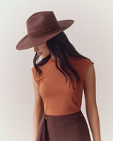 Person wearing sleeveless top, wide hat, and a skirt with side button.