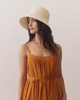 Person wearing dress and wide-brimmed hat looking to the side