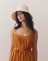 Person wearing a sleeveless dress and a wide-brimmed hat.