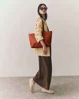 Person wearing sunglasses with blazer, pants, and tote bag