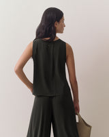 Person facing away wearing sleeveless top and holding a bag in one hand.