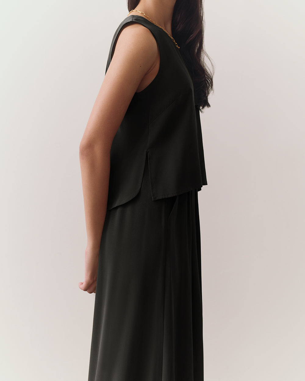 Person in sleeveless top and pants, standing sideways.