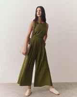 Person wearing sleeveless top and wide-leg pants standing indoors