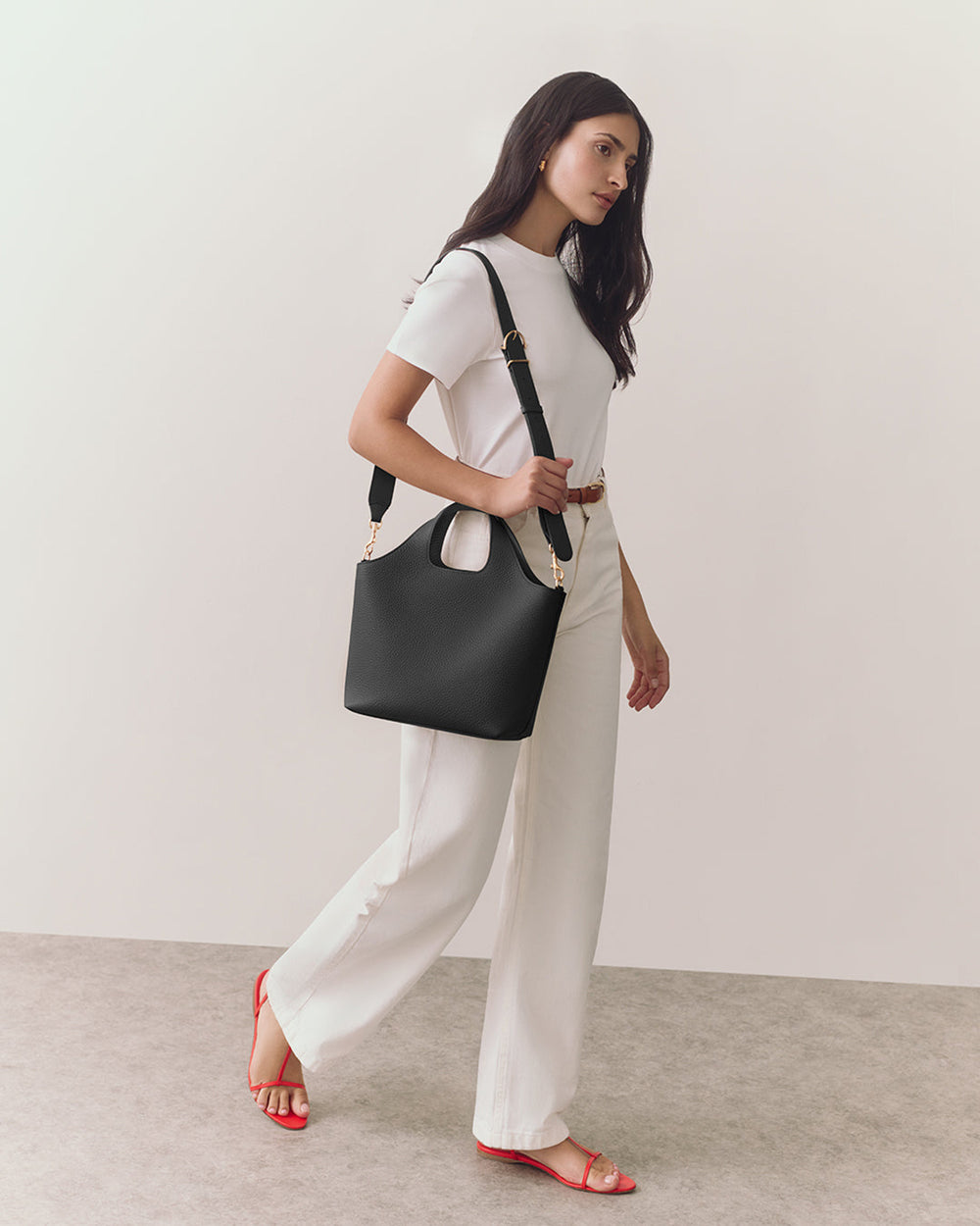 Person walking with a handbag on their shoulder, wearing a tee and pants