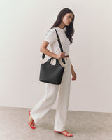 Person walking with a handbag on their shoulder, wearing a tee and pants