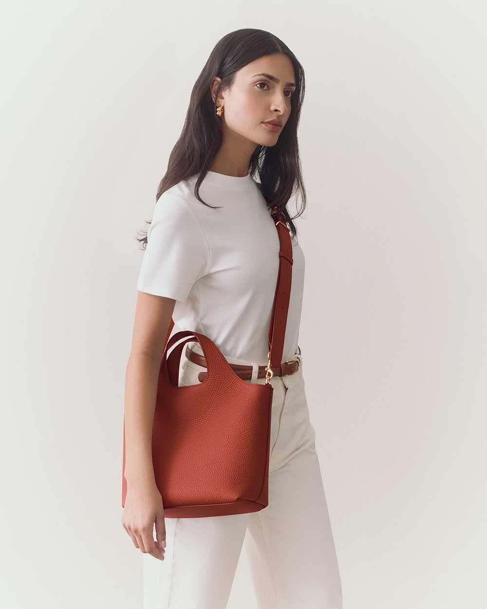 Person holding a handbag with a strap wearing a short-sleeve top and pants