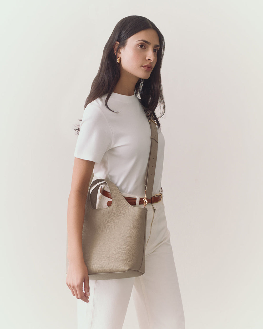 Person holding a handbag, wearing a short-sleeve top and pants.