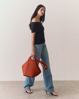Person in off-shoulder top with jeans holding a large handbag
