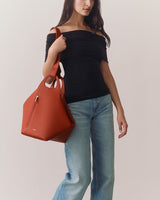 Person in a top and jeans holding a large handbag.