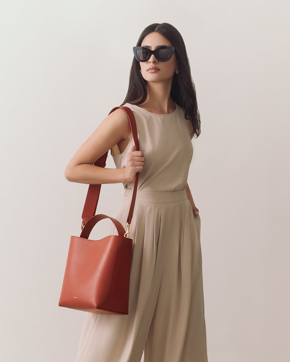 Linea Bucket Bag Person in sleeveless outfit carrying a shoulder bag, wearing sunglasses.