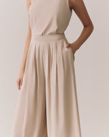 Person wearing a sleeveless top and wide-leg pants with hands in pockets