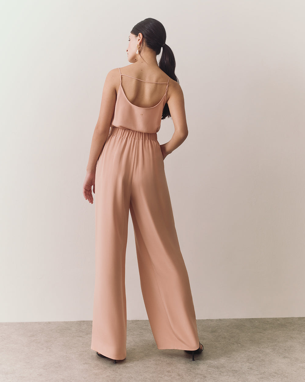 Woman walking in sleeveless top and wide-leg pants.