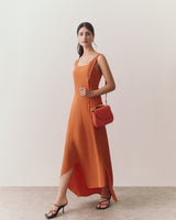 Person wearing a long dress and holding a bag over shoulder