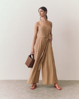 Person in jumpsuit holding a handbag, wearing sandals.