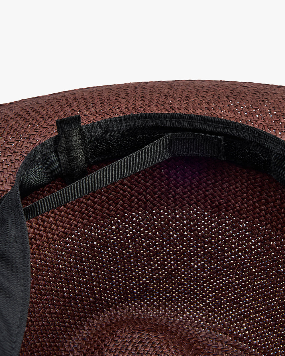 Inside view of a hat with adjustable strap and woven texture.