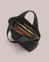 Open handbag with visible contents including a book, wallet, and pen.