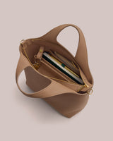 Open handbag with notebooks and pens inside, viewed from above