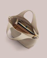 Open handbag with a notebook, pen, wallet, and straps visible inside.