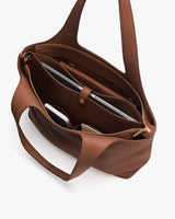 Open tote bag with a laptop, notebook, and small items inside.