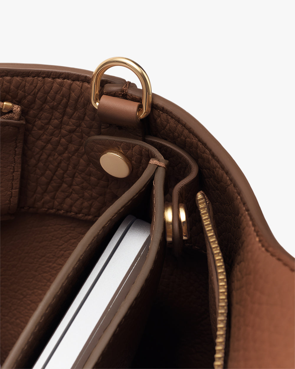 Bag interior with a zipped pocket, a laptop sleeve button, and a gold loop detail.
