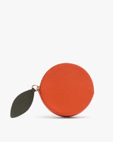 Round leather coin purse with a leaf-shaped zipper pull.