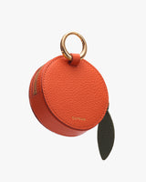 Round, leather coin purse with a zipper and metal ring.