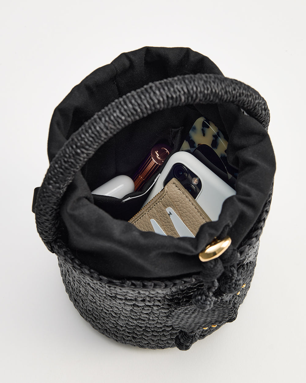 Woven bucket bag containing cosmetics and wallet viewed from above.