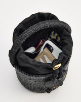 Woven bucket bag containing cosmetics and wallet viewed from above.