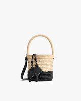 Woven bucket bag with handle and tassel details.