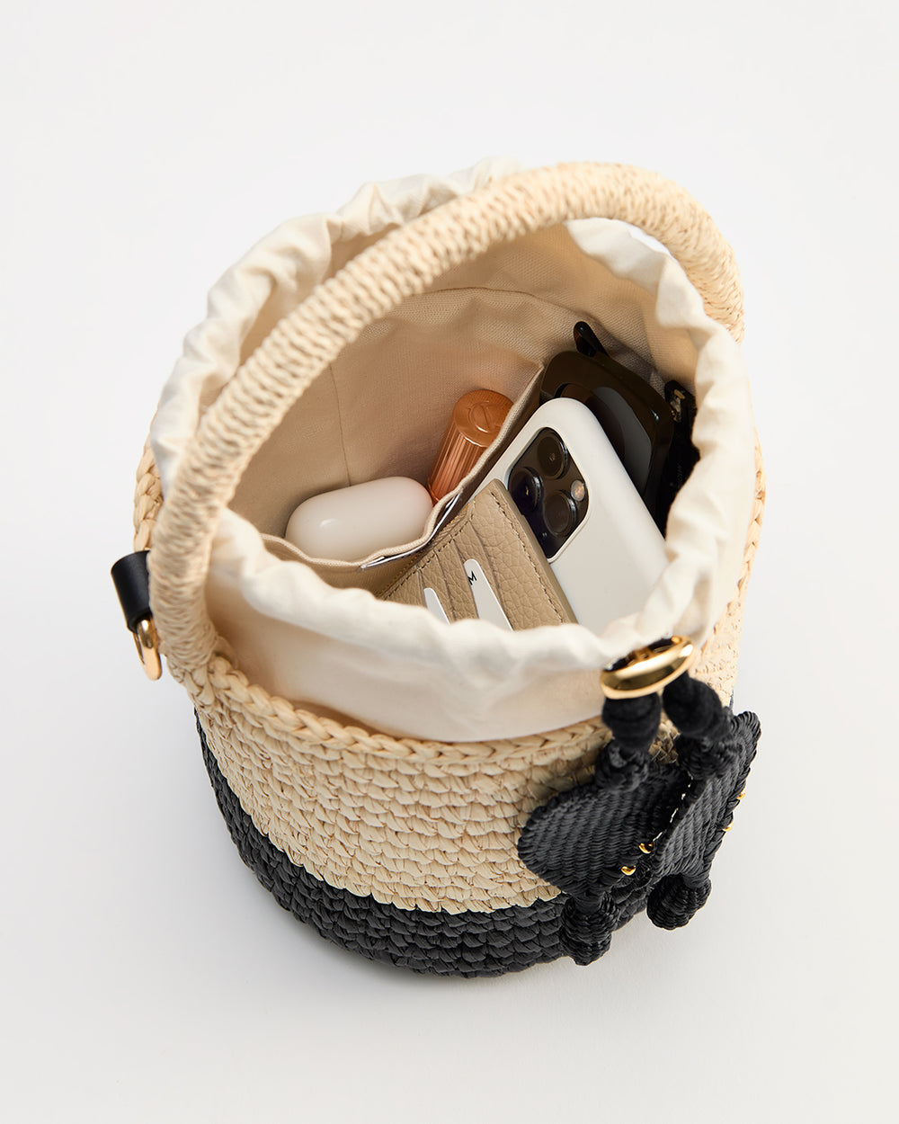 Toquilla Mini Bucket Bag Woven bucket bag with phone, earbuds, lipstick, cards inside.