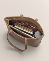Open handbag showing organized contents including books, a pen, sunglasses, and a water bottle.