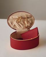 Open jewelry case with earrings and necklace inside, wallet beside it.