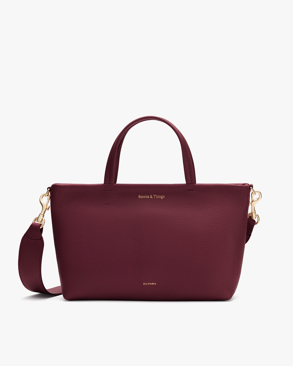 A handbag with a top handle, shoulder strap, and small gold embossed text.