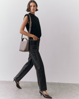 Person walking with handbag wearing sleeveless top and pants.