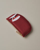 Wallet with cards partially visible and closed zipper on a neutral surface.