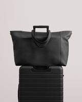 Travel bag resting on rolling luggage