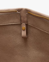 Interior view of an open leather bag with zipper and snap detail