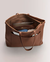 Open travel bag with visible interior pockets and packing items inside and outside.