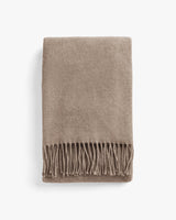 Folded blanket with fringed edges.