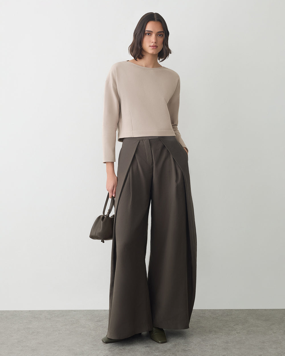 Fleece Cinched Top Person wearing a long-sleeve top and wide-leg pants holding a small bag in a studio setting.