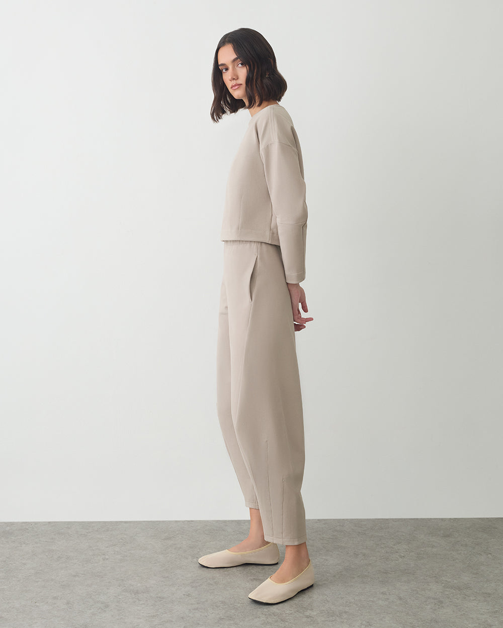 Person in a long-sleeve top and pants standing sideways.