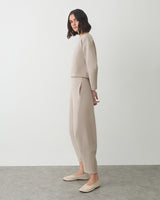 Person standing in a side pose wearing a matching top and pants with flats.