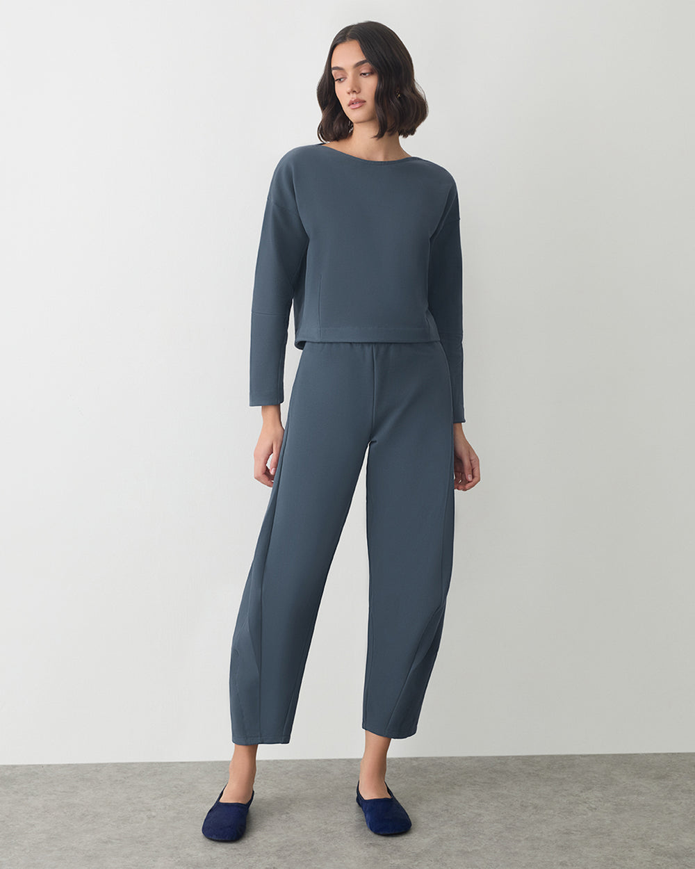 Fleece Barrel Pant Person wearing a long-sleeve top and trousers, standing indoors.