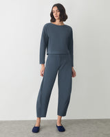 Person wearing a matching long-sleeve top and pants with slip-on shoes standing indoors.