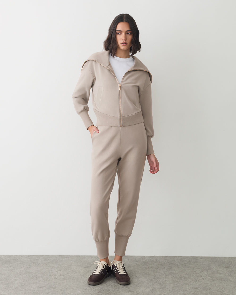 Person wearing matching zip-up hoodie and jogger pants with sneakers.