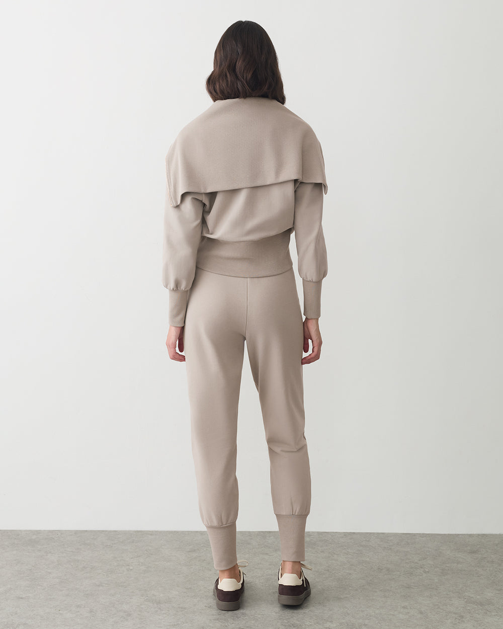 Person facing away, wearing matching pants and top in a studio setting.