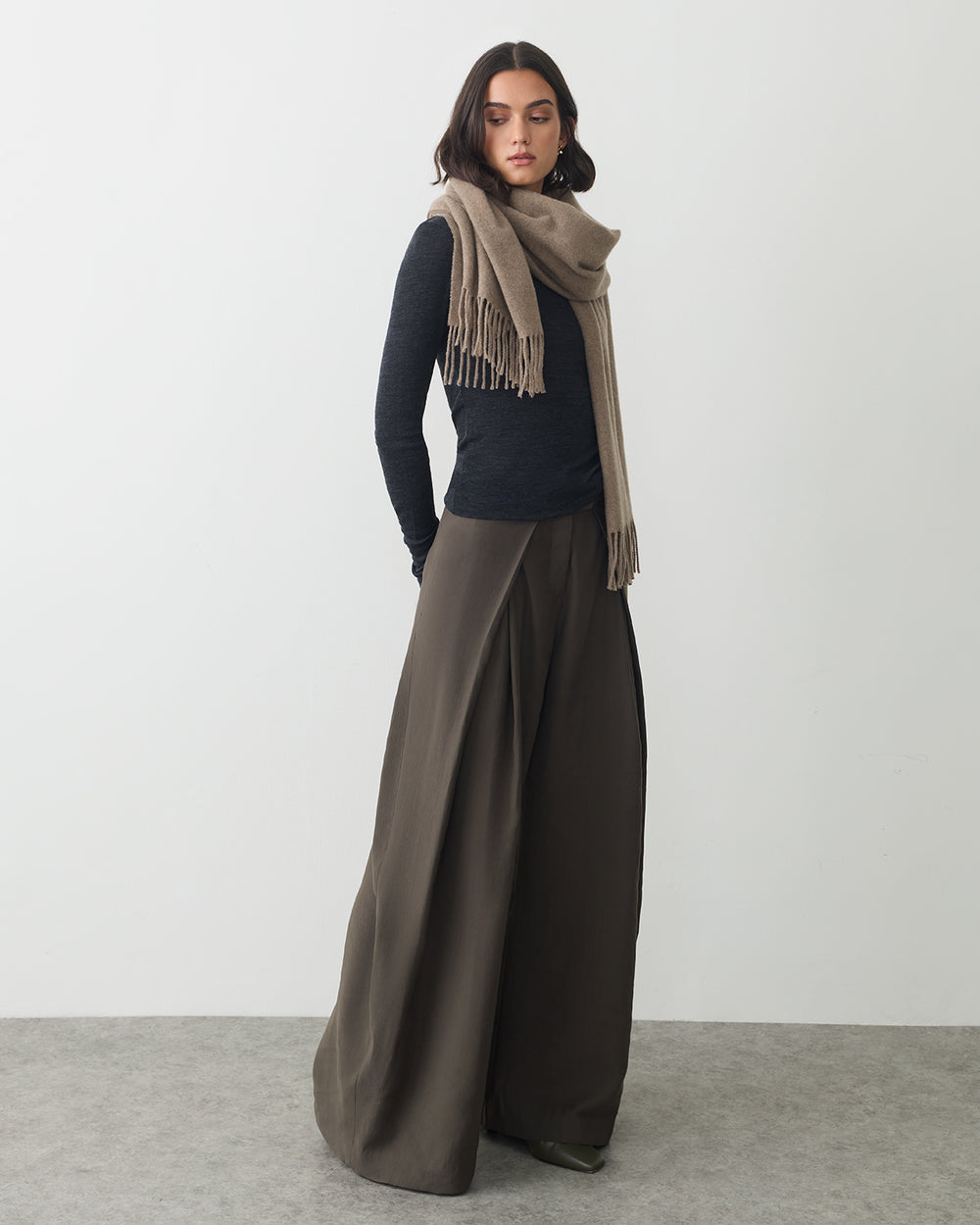 Person wearing wide-leg pants, long-sleeve top, and a scarf.