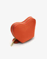 Heart-shaped zippered coin purse on a surface.
