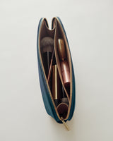 Makeup brushes and lipstick inside an open zippered cosmetic bag.